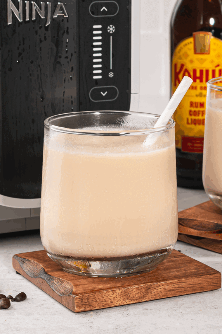 Glass of frozen White Russian slushy made with vodka, Kahlúa, and milk, served in a clear glass with a straw.