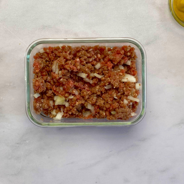 Mixing ground beef, chopped onion, Worcestershire sauce, salt, and pepper in a bowl before air frying at 375°F (190°C).