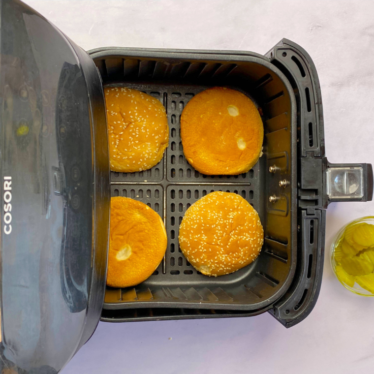 Soft sandwich buns toasting in the air fryer at 400°F for 1–2 minutes until lightly golden.