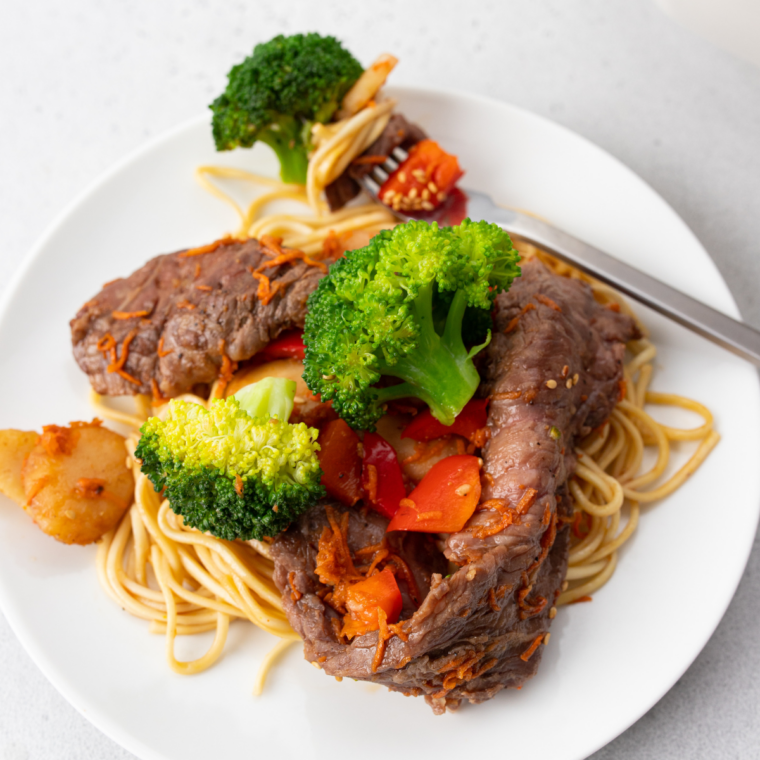Air fryer beef lo mein with sliced steak, broccoli, bell peppers, and noodles in savory sauce