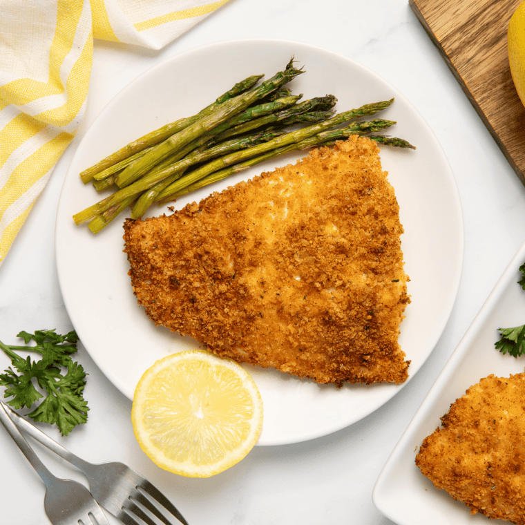 Crispy panko crusted red snapper fillet cooked in air fryer, golden brown and served with lemon wedges