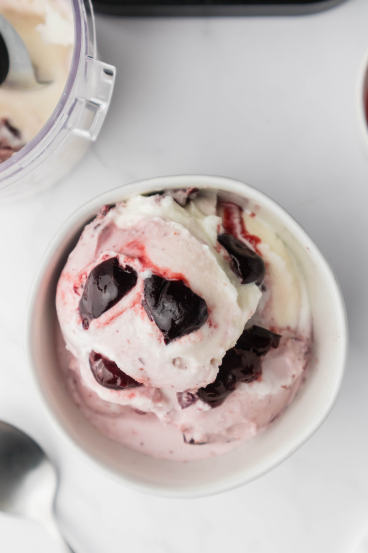 Homemade cherry gelato served in a bowl, topped with fresh cherries and a creamy texture.