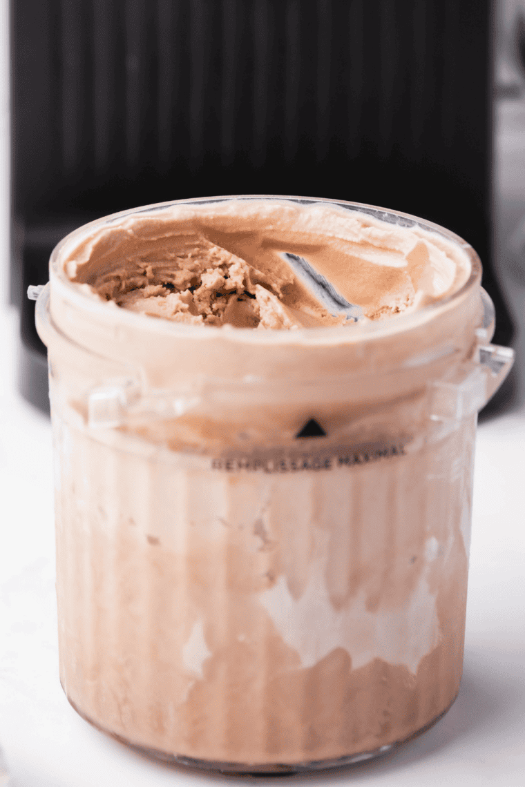 Frozen chocolate gelato pint placed into Ninja Creami machine before selecting gelato function.