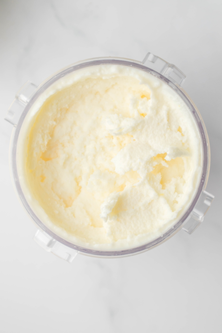 Creamy homemade lemon gelato made in the Ninja Creami topped with fresh lemon zest in a white bowl.