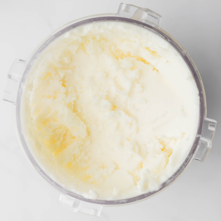 Pouring lemon gelato mixture into Ninja Creami pint and securing the lid before freezing.