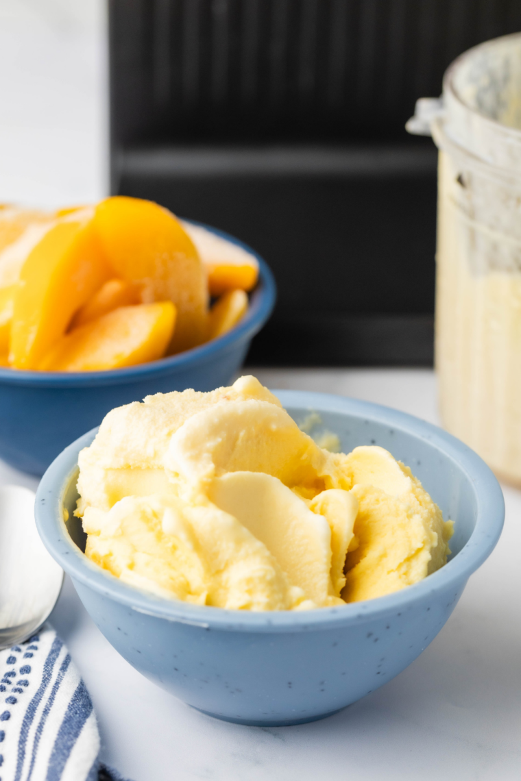 Creamy peach gelato made in Ninja Creami served in a bowl with fresh peach slices
