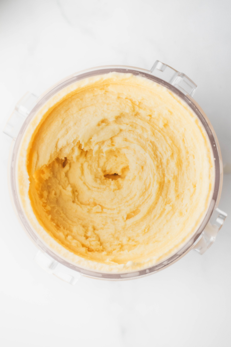 Scooping creamy peach gelato into bowl with smooth texture