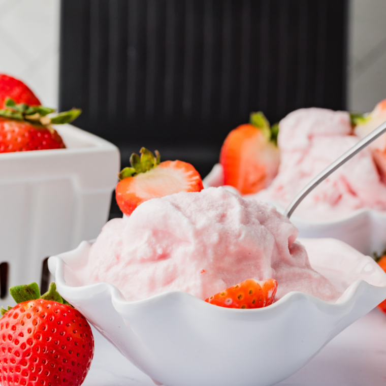 Creamy strawberry gelato scooped into a bowl, made in the Ninja Creami and topped with fresh strawberries.