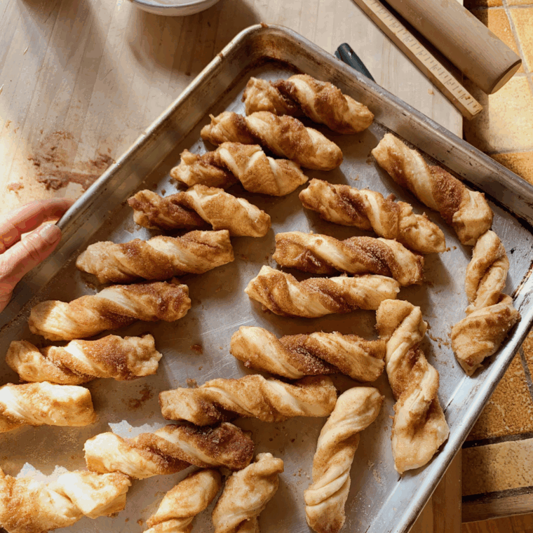 Golden cinnamon twists cooling on baking sheet before serving