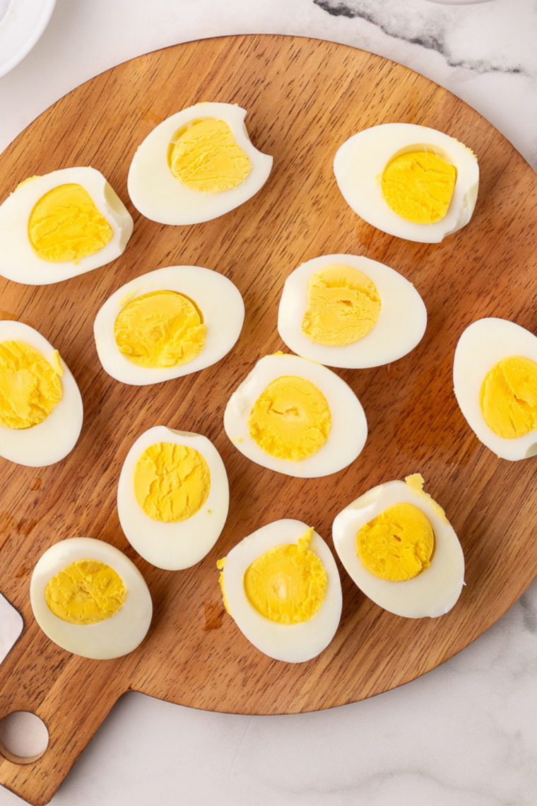 Peel and Slice: Peeled eggs sliced in half with yolks removed into a mixing bowl.