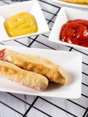 Alt Text: Crispy homemade corn dogs fresh from the air fryer with dipping sauces on the side.