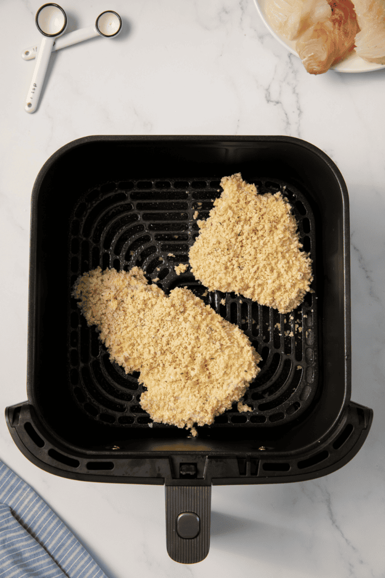 Coated haddock fillets cooking in air fryer at 400°F, golden and crispy, flipping halfway through.