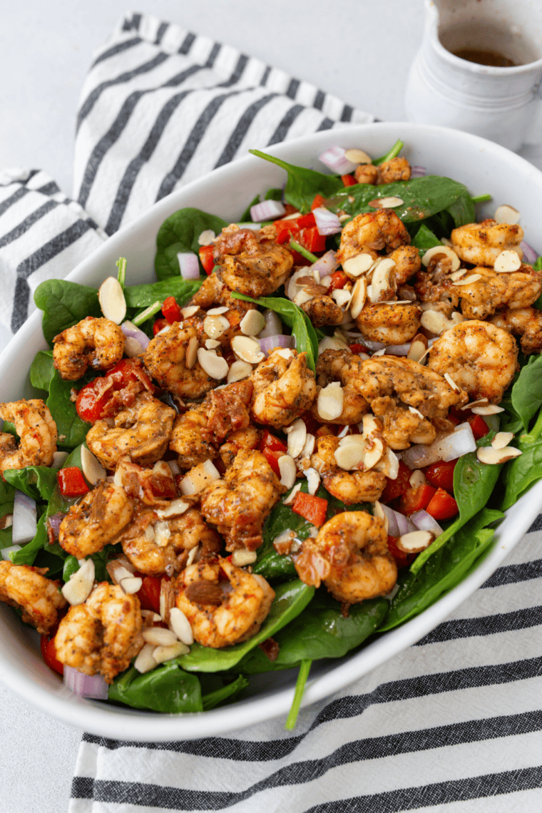 Air fryer shrimp served over fresh spinach salad with roasted red peppers and homemade dressing.