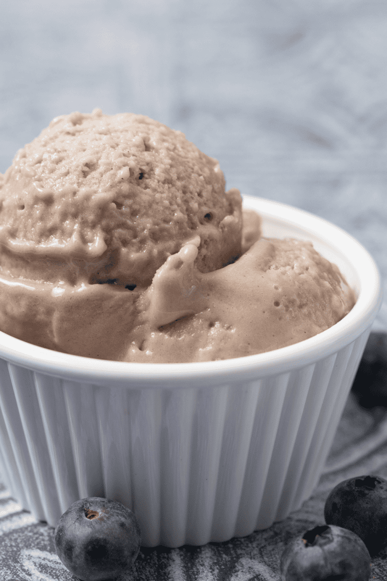 Smooth and creamy blueberry gelato made in a Ninja Creami, served in a bowl with fresh blueberries on top.