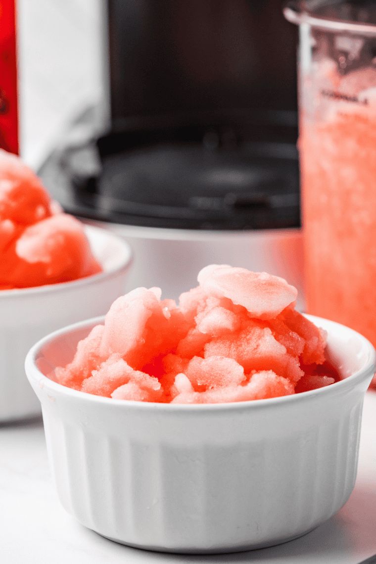 Bright red cherry Italian ice in a clear glass, smooth and icy texture, garnished with fresh cherries.
