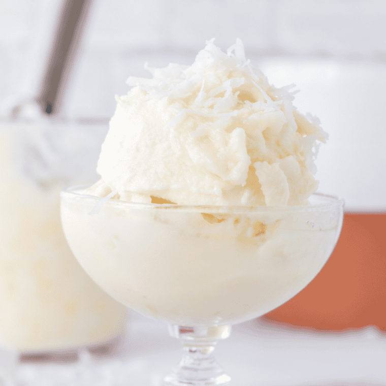 Creamy coconut gelato served in a bowl with a spoon, topped with shredded coconut.