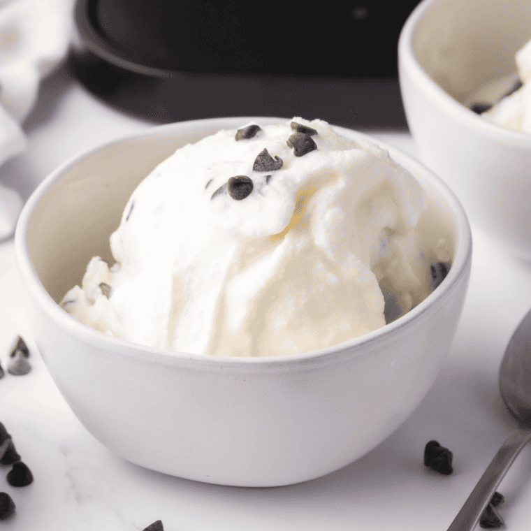 A scoop of Ninja Creami Fior Di Latte sweet cream gelato in a white bowl, topped with fresh berries and mint, showing a smooth and creamy texture.