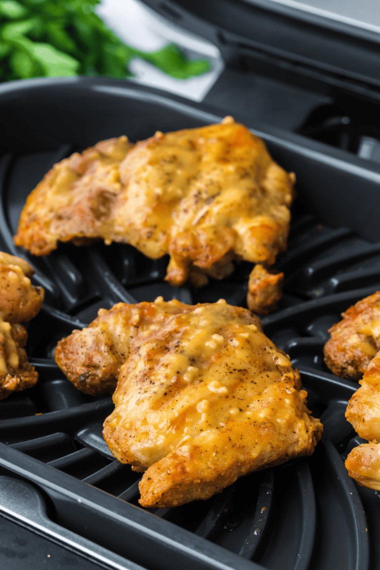 Golden, grilled boneless chicken thighs cooked in a Ninja Foodi, served on a plate.