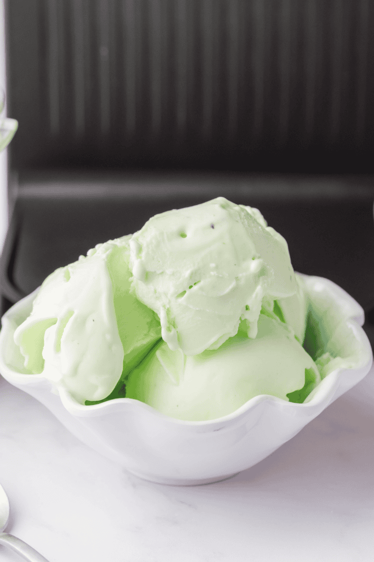 Bright green St. Patrick’s Day ice cream scooped into a bowl with festive sprinkles.