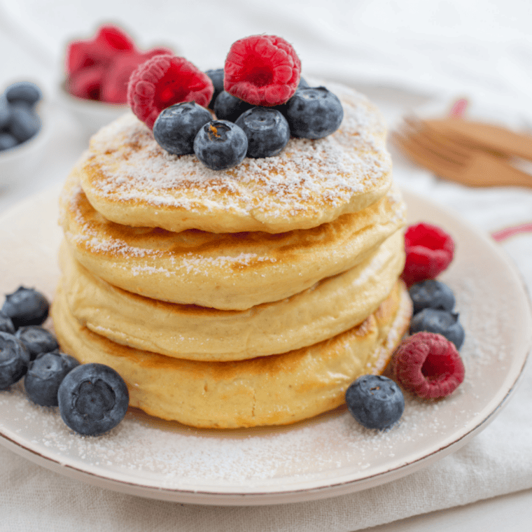 Stack of fluffy golden pancakes topped with butter and syrup, inspired by Perkins Restaurant classic diner-style pancakes served on a white plate.
