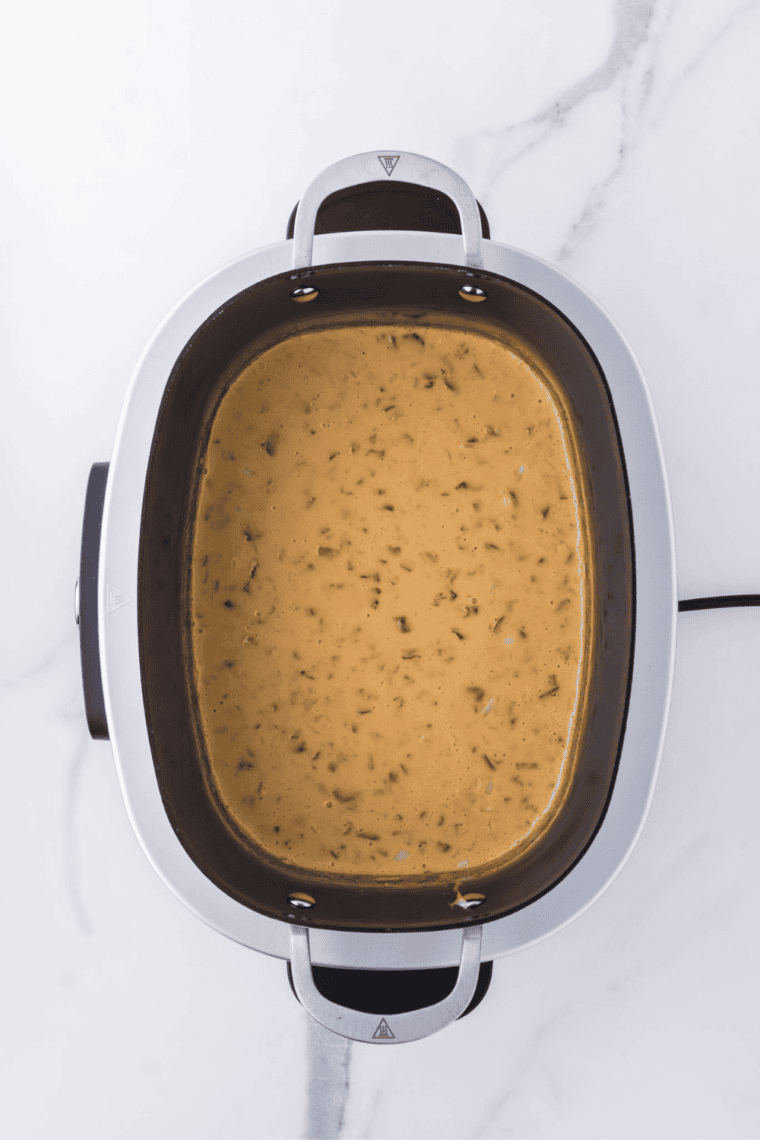 creamy crockpot cream cheese dip served warm in slow cooker with tortilla chips for dipping