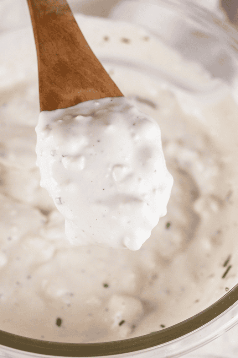 Whisking mayonnaise, buttermilk, and sour cream in a bowl until smooth and creamy.
