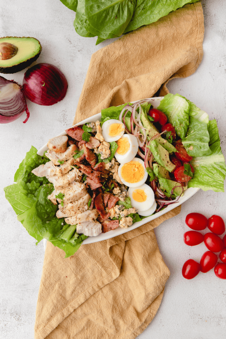 Fresh Cobb salad inspired by First Watch with romaine lettuce, grilled chicken, crispy bacon, boiled eggs, avocado slices, cherry tomatoes, and creamy dressing.