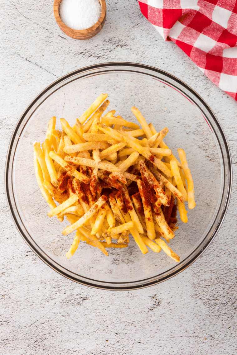 Small bowl filled with mixed spices including salt, paprika, garlic powder, onion powder, black pepper, sugar, celery salt, turmeric, and mustard powder being stirred together into a blended seasoning mix.