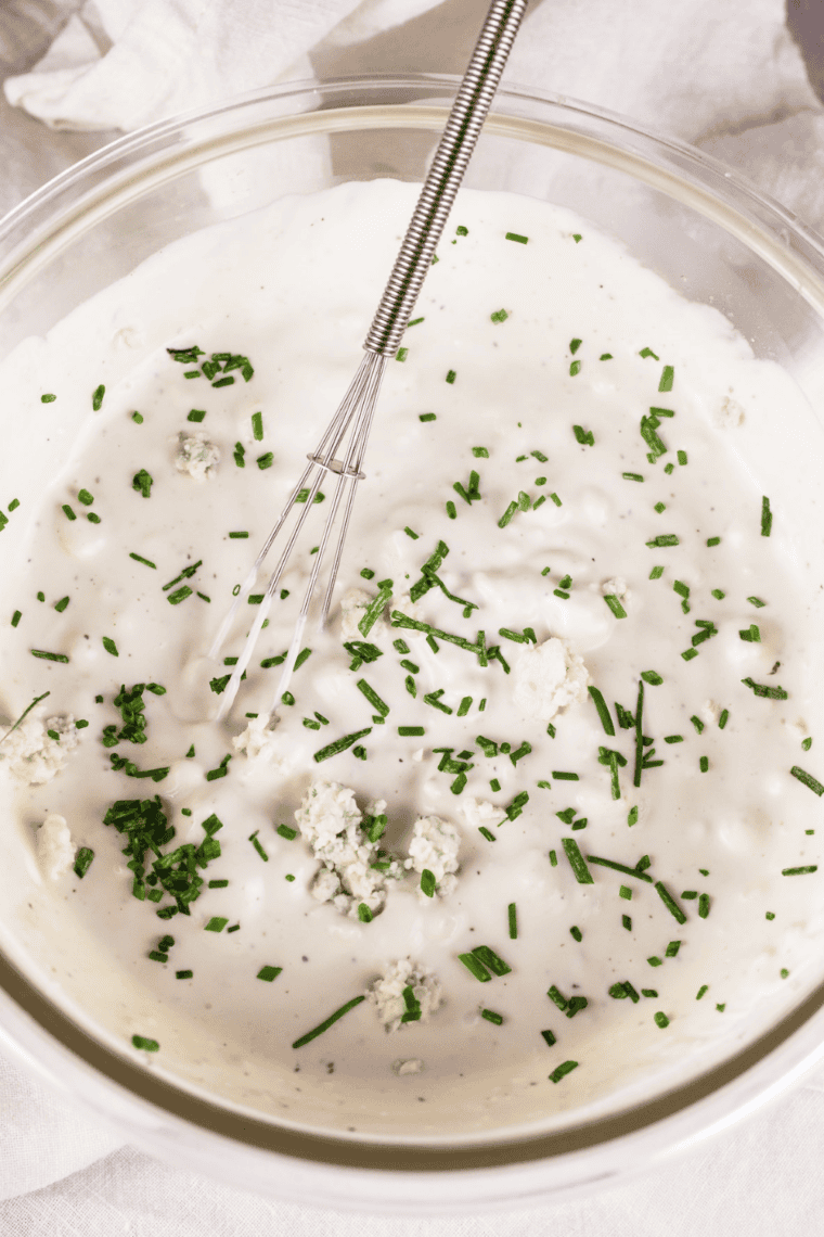 Covered bowl of ranch dressing chilling in refrigerator to let flavors blend before serving.