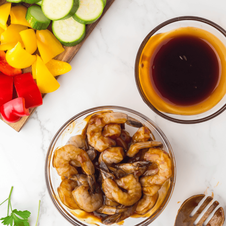 Combining ingredients in saucepan: Soy sauce, brown sugar, honey, garlic, ginger, and vinegar being whisked in a saucepan over heat.