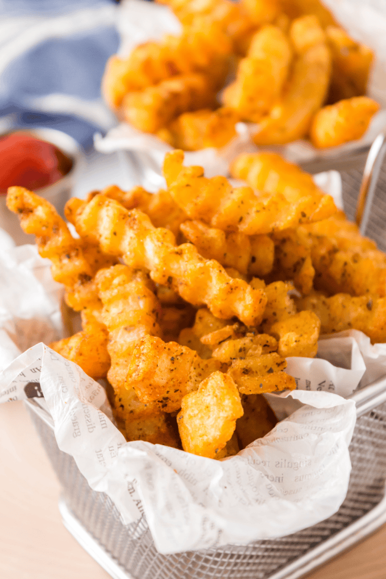 Bowl of homemade Zaxby’s fry seasoning sprinkled over crispy golden fries for extra flavor.