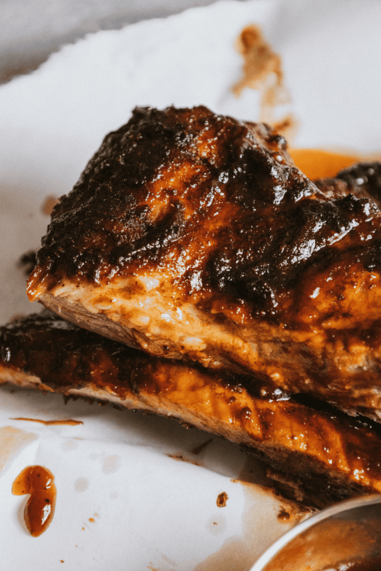 Close-up of juicy air fryer beef ribs with caramelized BBQ glaze and a deep crusty bark, served on a white plate