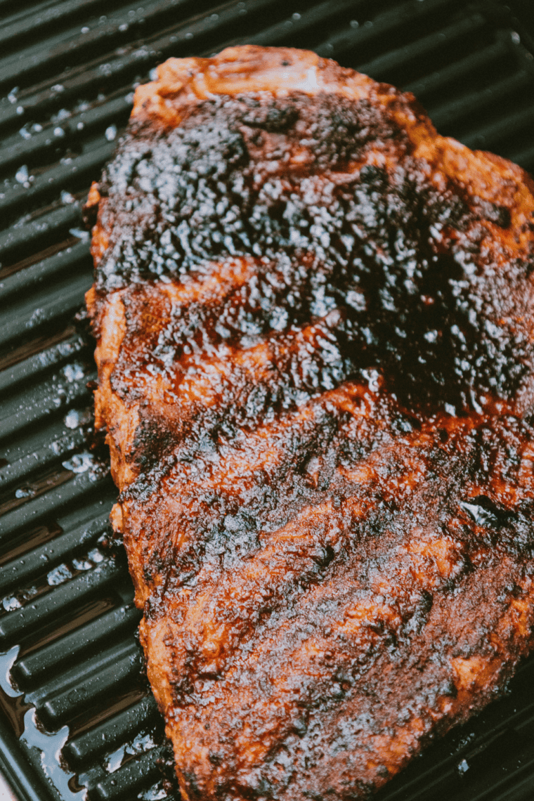 Seasoned beef ribs cooking meat-side up in an air fryer at 320 degrees