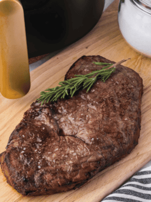 Sliced air fryer round steak on a wooden cutting board showing a juicy pink medium-rare center