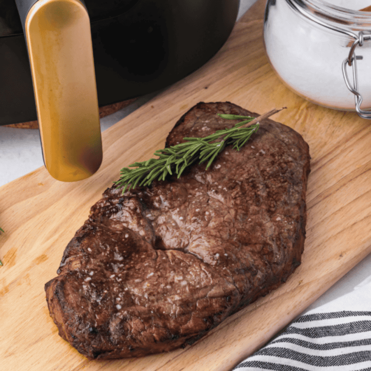 Sliced air fryer round steak on a wooden cutting board showing a juicy pink medium-rare center