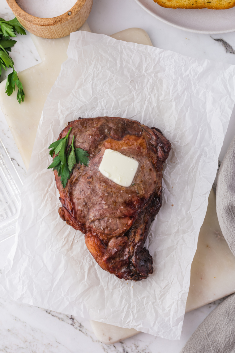 Air fryer basket holding seasoned ribeye steak mid-cook