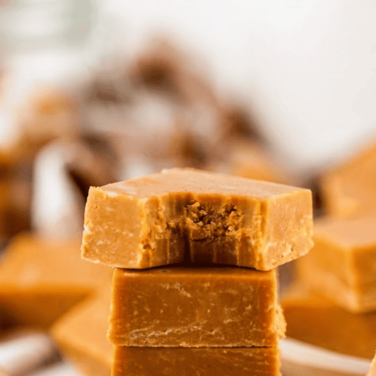 Squares of chocolate caramel marble fudge stacked on parchment, with caramel swirls visible on top
