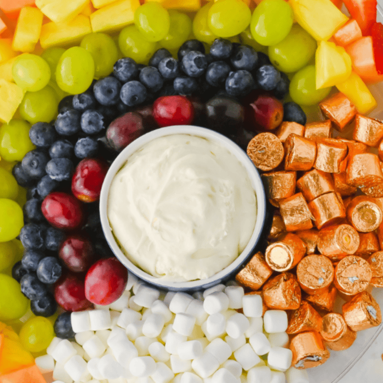 Creamy copycat Jason's Deli fruit dip in a white bowl surrounded by fresh strawberries, apple slices, and grapes