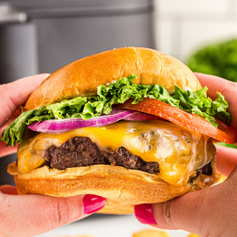 Cooked smash burger flipped in skillet with melted American cheese on top, finishing the McDonald’s-style cheeseburger.