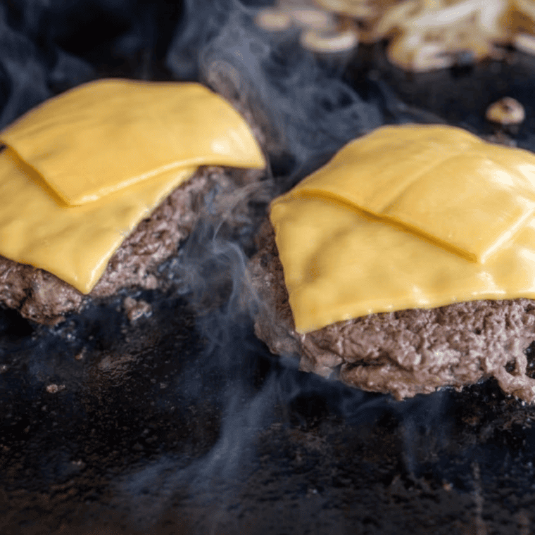 Hamburger buns steaming cut-side down in pan with lid for soft pillowy texture like McDonald’s buns