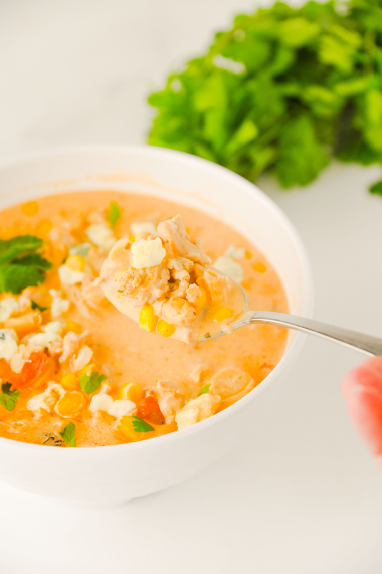 Creamy buffalo chicken chili served in a white bowl with tortilla chips on the side