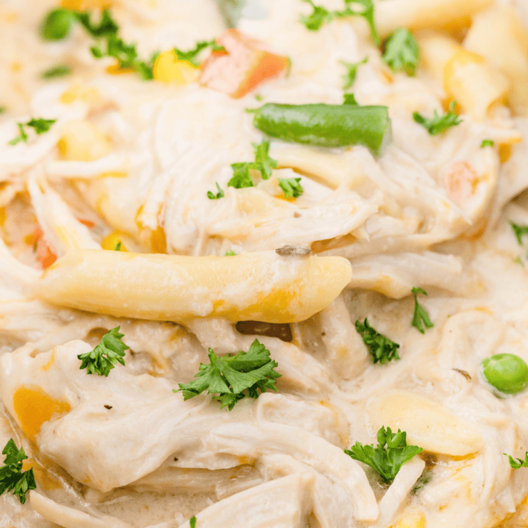 Slow cooker filled with cheesy chicken pot pie pasta and mixed vegetables ready for dinner.