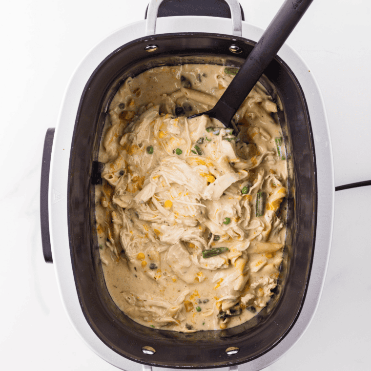 Finished crock pot chicken pot pie pasta in a white bowl, topped with fresh chopped parsley and cracked black pepper.