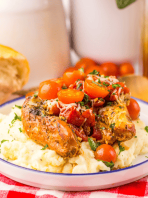 Slow cooker bruschetta chicken topped with fresh tomatoes, basil, and melted mozzarella in a white bowl