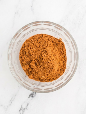 Small glass bowl filled with homemade chili seasoning mix made with paprika, chili powder, cumin, and garlic powder.