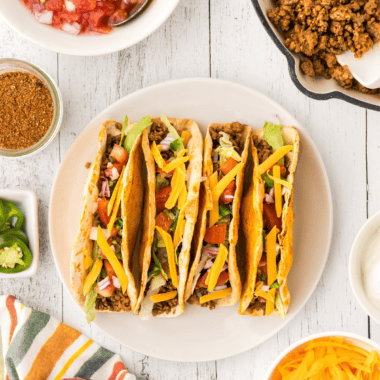 Homemade McCormick taco seasoning copycat in a small glass jar with a measuring spoon on a wooden board