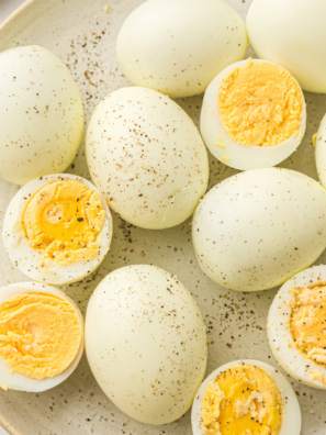 Ninja Crispi hard boiled eggs peeled and sliced on a white plate with seasoning