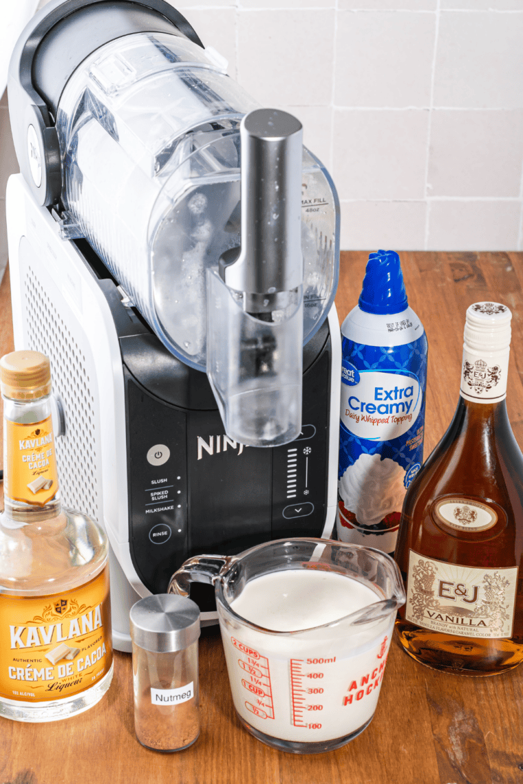 Pitcher with vanilla brandy, crème de cacao, and heavy cream being stirred together into a smooth mixture