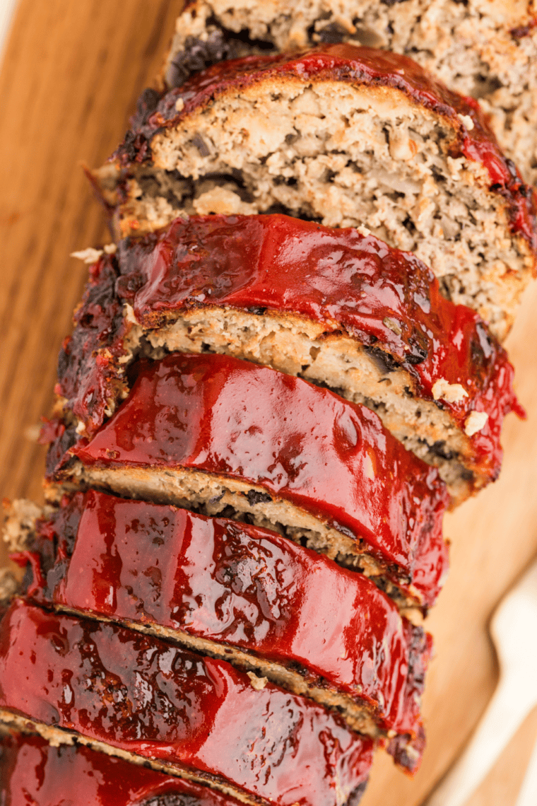 Sliced one pound meatloaf on a plate showing a moist center and caramelized ketchup glaze on top.