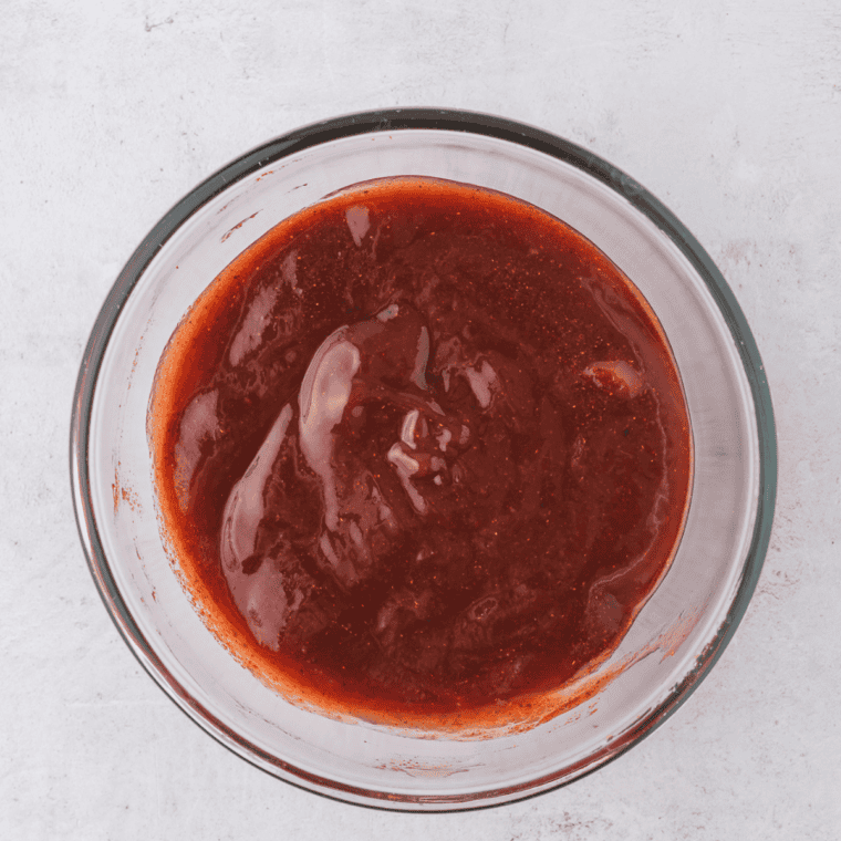 Make and Apply the Glaze
Sweet and tangy ketchup glaze being brushed over a partially baked meatloaf on a sheet pan.